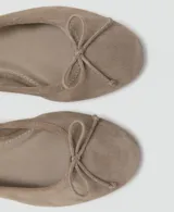 Zapato plano tipo chatita o ballerina de piel bovina en color taupe, con diseño clásico de punta redonda y pequeño detalle de lazo en el empeine.