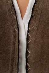 Saco básico de punto color marfil, confeccionado en lambswool, con corte entallado tipo chaquetita. Destaca por detalles de blonda tejida en los puños y a lo largo de la abertura frontal, con bordes en color contrastante.