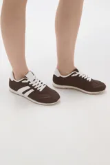 Zapatillas de estilo urbano color marrón con detalles en blanco, confeccionadas en material textil y sintético, con cordones blancos y suela de goma.