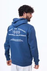 Buzo tipo canguro con capucha, confeccionado en felpa de algodón y poliéster. Presenta un diseño estampado en la espalda con tipografía y detalles gráficos.