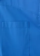 Camisa de popelín color azul, de diseño oversize y sin mangas, con cuello camisero, bolsillo parche delantero y cierre frontal con botones.