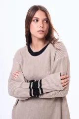 Sweater de punto color marrón con cuello redondo, puños y cuello con detalles de rayas blancas en contraste. De corte holgado y manga larga.