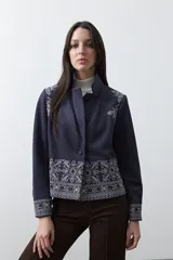 Blazer de gamuza color terracota con bordados decorativos en color crudo en solapas, puños y ruedo. Presenta corte recto, solapas clásicas y cierre frontal con un botón forrado.