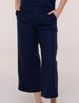 Pantalón crop de lino y algodón color blanco, con calce holgado, pierna ancha de corte recto y cintura elástica. Presenta bolsillos laterales y detalle de puntilla aplicada en el frente.