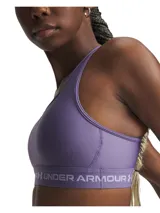 Top deportivo Under Armour de soporte medio, color violeta, con diseño de espalda cruzada y banda elástica inferior con logo de la marca. Confeccionado en tejido HeatGear de doble capa, de secado rápido y alta transpirabilidad.