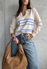 Sweater de punto fino color beige, con cuello polo y escote en V. Presenta tres rayas horizontales azules en el pecho y mangas largas con puños acanalados.