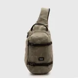 Bolso tipo bandolera de diseño ergonómico en color verde oliva, con acabado encerado. Cuenta con una correa ajustable, cierres waterproof y correas de compresión frontales con hebillas negras. Incluye etiqueta de la marca en el frente.