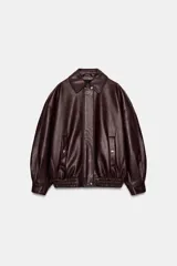 Cazadora estilo bomber de efecto piel en color bordó, con cuello solapa, manga larga, bolsillos delanteros de vivo con botón a presión y bajo elástico. Cierre frontal con cremallera oculta y botones a presión.