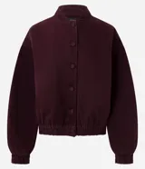 Campera estilo bomber de sarga color bordó, con cuello alto, cierre frontal con botones forrados, mangas largas con puños elásticos y bajo ajustado.