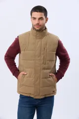 Chaleco reversible capitoneado de corte estándar, con cuello alto, cierre frontal de cremallera y botones a presión. Cuenta con bolsillos laterales y un bolsillo vertical en el pecho.