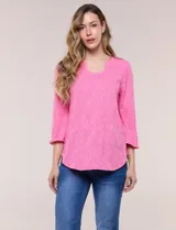 Blusa rosada con textura en relieve de motivos florales, cuello redondo con pequeña muesca y mangas tres cuartos.