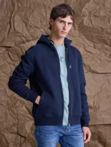 Canguro con cierre frontal completo, confeccionado en tejido fleece de color azul marino. Presenta capucha con cordones ajustables, bolsillos laterales y puños y ruedo acanalados.