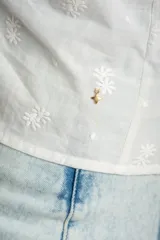 Blusa marrón de algodón con bordados sutiles, escote en V, mangas cortas abullonadas y detalle de fruncido con cordón ajustable en el centro del frente.