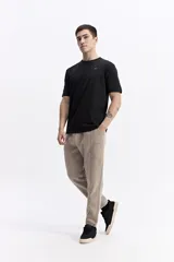 Pantalón de jogging negro de algodón y poliéster, con puños ajustados en los tobillos, cintura elástica con cordón y costuras verticales marcadas en el frente.