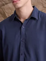 Camisa de manga larga color azul marino, con cuello clásico y cierre frontal de botones.