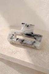 Pinza de pelo rectangular con diseño efecto mármol en tonos gris, blanco y negro.