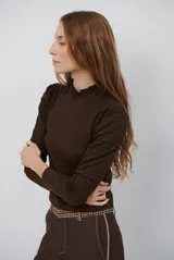 Polera de manga larga con cuello alto y detalle de volados en el borde. Confeccionada en tejido acanalado de textura suave y ajuste al cuerpo.