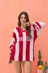 Remerón tejido de punto con diseño de rayas verticales rojas y rosadas, escote en V y la inscripción "BRASIL" en el frente.