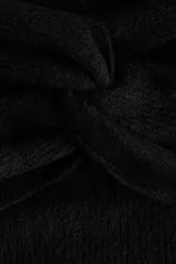 Buzo de punto acanalado negro con escote off-the-shoulder y detalle de nudo frontal. Presenta mangas largas y corte ajustado.