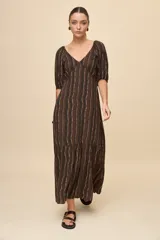Vestido largo marrón con estampado de rayas verticales onduladas, escote en V, mangas 3/4 abullonadas y falda con recorte y vuelo en el bajo.