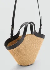 Bolso tipo capazo de fibras naturales con estructura rígida en forma de abanico, con detalles en cuero sintético negro en los bordes superiores y asas. Incluye una correa larga ajustable y cierre de nudo.