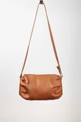 Bandolera de cuero color marrón, con correa larga regulable y cierre superior.