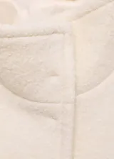 Chaqueta de corte recto confeccionada en mezcla de lana y viscosa, color crema. Presenta cuello alto, cierre frontal con botones ocultos, manga larga y dos bolsillos con solapa en la parte delantera.