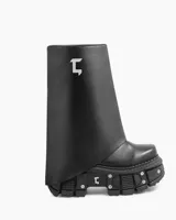 Bota negra de cuero ecológico con caña alta asimétrica y suela track con detalles metálicos.