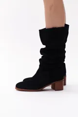 Bota de caña alta color beige, confeccionada en cuero gamuzado. Tiene taco de madera y puntera redondeada.