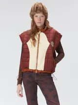 Chaleco de corte cuadrado con diseño bicolor en tonos terracota y crema. Presenta cierre frontal metalizado, parches de nylon en el pecho, interior forrado en corderito y cordón ajustable en el ruedo.