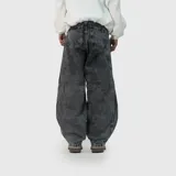Pantalón jean de corte ultra baggy, color negro con efecto lavado ácido. Presenta costuras curvas decorativas en la parte superior y diseño de piernas amplias con ajuste en los tobillos.