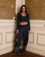 Pantalón de jogging negro, tiro medio, con cintura elástica fruncida y roturas en las rodillas.