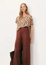 Blusa de manga corta con cuello redondo y estampado de cuadrícula blanca sobre fondo color tostado.