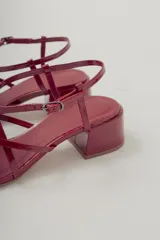Sandalia de tiras finas color rojo brillante, con puntera cuadrada y taco ancho de altura media. Posee tira ajustable con hebilla en el tobillo.