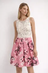Vestido corto sin mangas con cuerpo de tul transparente bordado con motivos florales y falda amplia en color rosado con estampado de flores grandes.