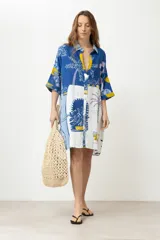 Vestido camisero corto con estampado de paisaje en tonos azules y amarillos.