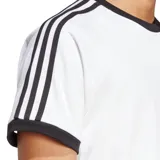 Remera blanca de algodón con cuello redondo y mangas cortas con ribete azul marino. Presenta las tres rayas características de Adidas en azul marino en los hombros y el logo de Adidas bordado en el pecho.