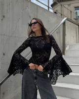 Blusa de encaje negro con diseño floral, de corte ajustado al cuerpo y mangas largas con terminación acampanada y amplia.