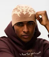 Gorro de punto doble faz con diseño tribal abstracto en tonos beige y marrón. Confeccionado en tejido acrílico suave, ofrece aislamiento térmico y un ajuste cómodo.