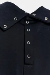 Top negro de hilatura de algodón, sin mangas y con cuello subido. Cuenta con cierre en la espalda mediante botones a presión.