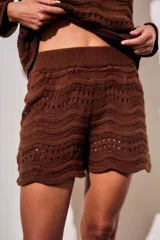 Short tejido de punto con diseño de ondas y calados, color blanco. Presenta cintura elástica acanalada y corte mini.