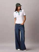 Chomba Calvin Klein de algodón con textura de punto fino, color blanco, con cuello polo y puños en contraste color verde. Presenta media cremallera frontal y diseño de manga corta.