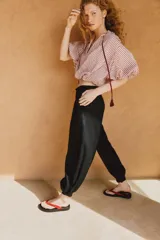 Pantalón bombacho de tiro medio confeccionado en lino, color negro, con pernera abullonada y bajo acabado en puño con botón.