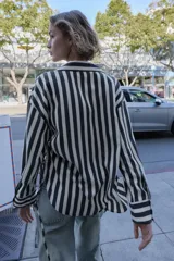 Camisa de cuello solapa con escote pico y manga larga. Presenta un bolsillo delantero de plastrón y bajo con aberturas laterales con cordones ajustables. Cierre frontal con botones.