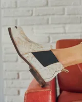 Botín Chelsea de cuero color beige con elástico lateral negro, puntera redondeada y suela plana.