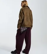 Campera de gamuza sintética color marrón, con cuello inglés, cierre frontal con botones metálicos, bolsillos delanteros y elástico en el bajo y puños.