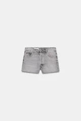 Shorts de denim gris claro con efecto lavado, tiro bajo y corte ancho (baggy). Presenta cinco bolsillos y cierre frontal con cremallera y botón metálico.