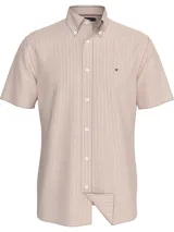 Camisa de manga corta Tommy Hilfiger confeccionada en tejido oxford de algodón. Presenta un diseño a rayas verticales en color naranja y blanco, cuello con botones y logo de la marca bordado en el pecho.