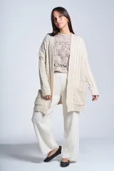 Saco tejido color crema con diseño de ochos, bolsillos frontales y corte holgado.