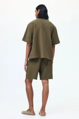 Pantalón corto de tejido texturizado verde militar, con corte relajado, cintura elástica con cordón de ajuste y bolsillos laterales.
